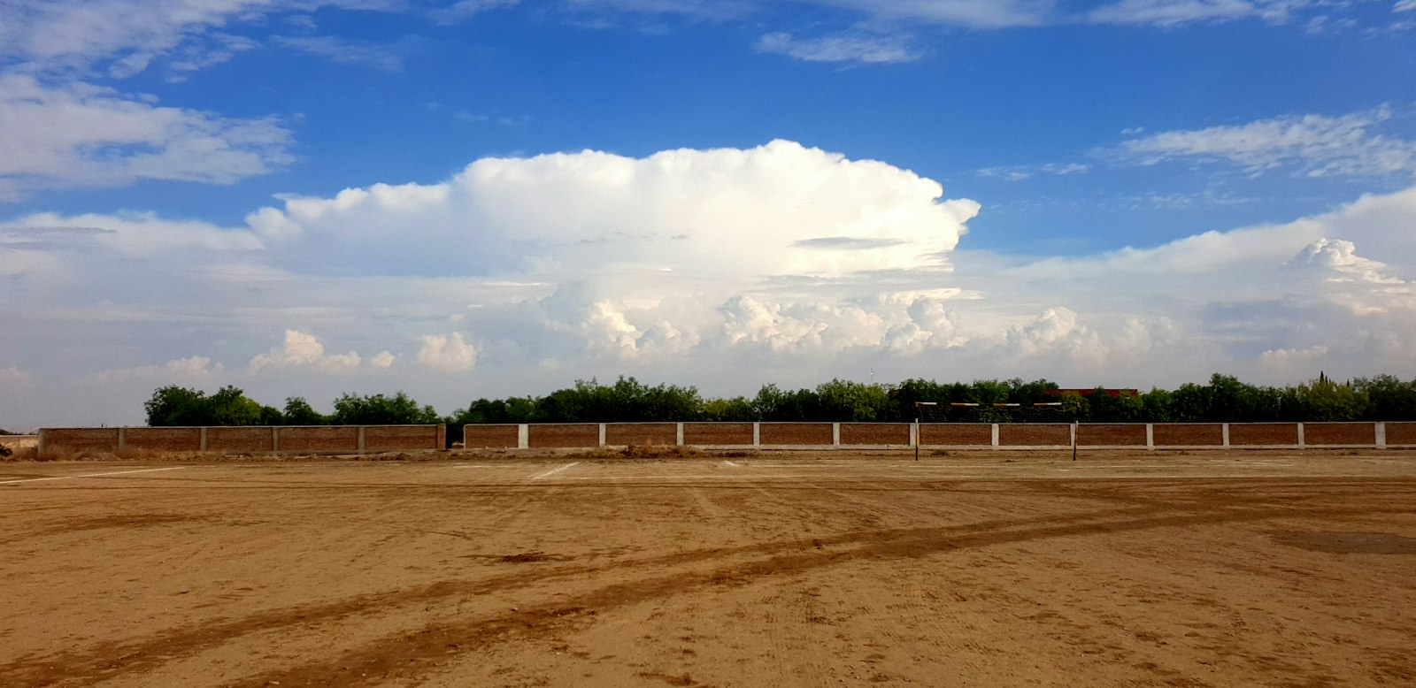 Open sand yard bordered by a wall, illustrative of the working grounds at a turnkey equestrian center in the Central Algarve